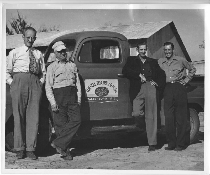 Vintage photo of four Coastal Electric Cooperative employees standing in front of a CEC truck.