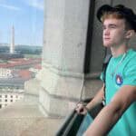 A person looks out over Washington, D.C., with the Washington Monument visible in the distance on a clear day.