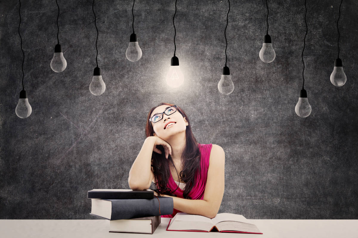 Female college student with books and bright light bulb above her head as a symbol of bright ideas