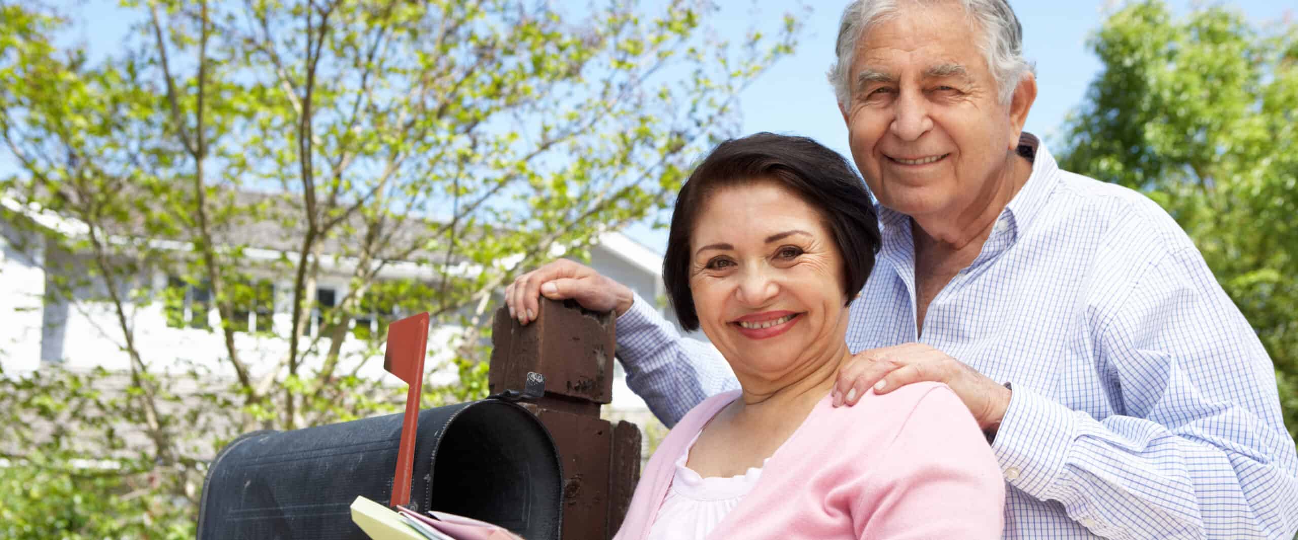 Smiling senior couple at their mailbox
